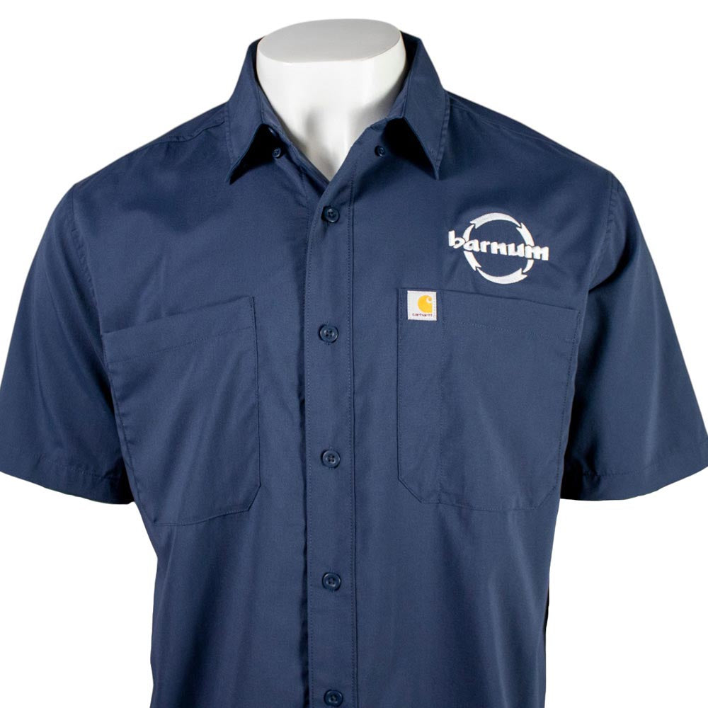 Close up of chest of navy blue button up shirt with two chest pockets and a white HH Barnum logo.