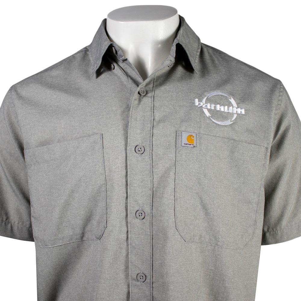 Close up of chest of grey button up short sleeve with two chest pockets and the hh barnum logo. 