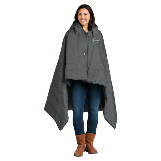 Woman wearing a gray hooded puffy poncho with a barnum logo on the left chest. 